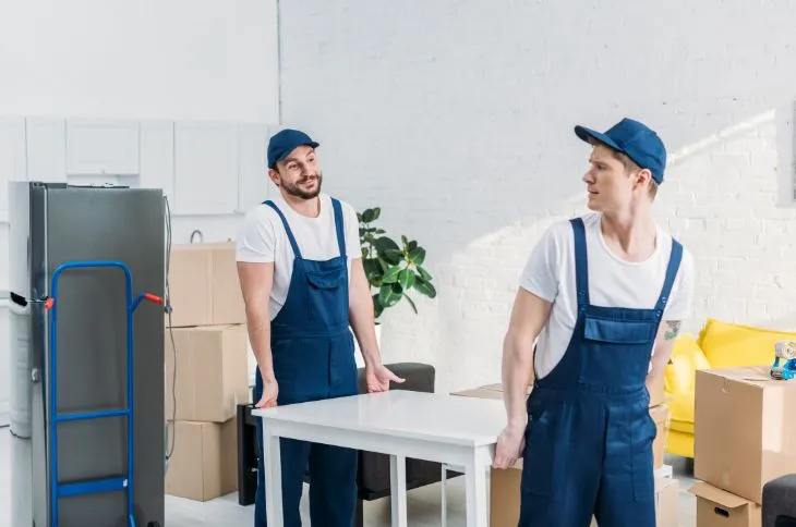 Movers carry table for customer